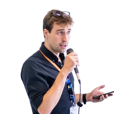 Tim Theys speaking at an event, holding a microphone