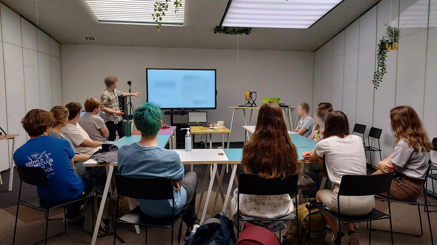 A focus group session: participants seated around tables facing a central screen, with one moderator presenting the concept.